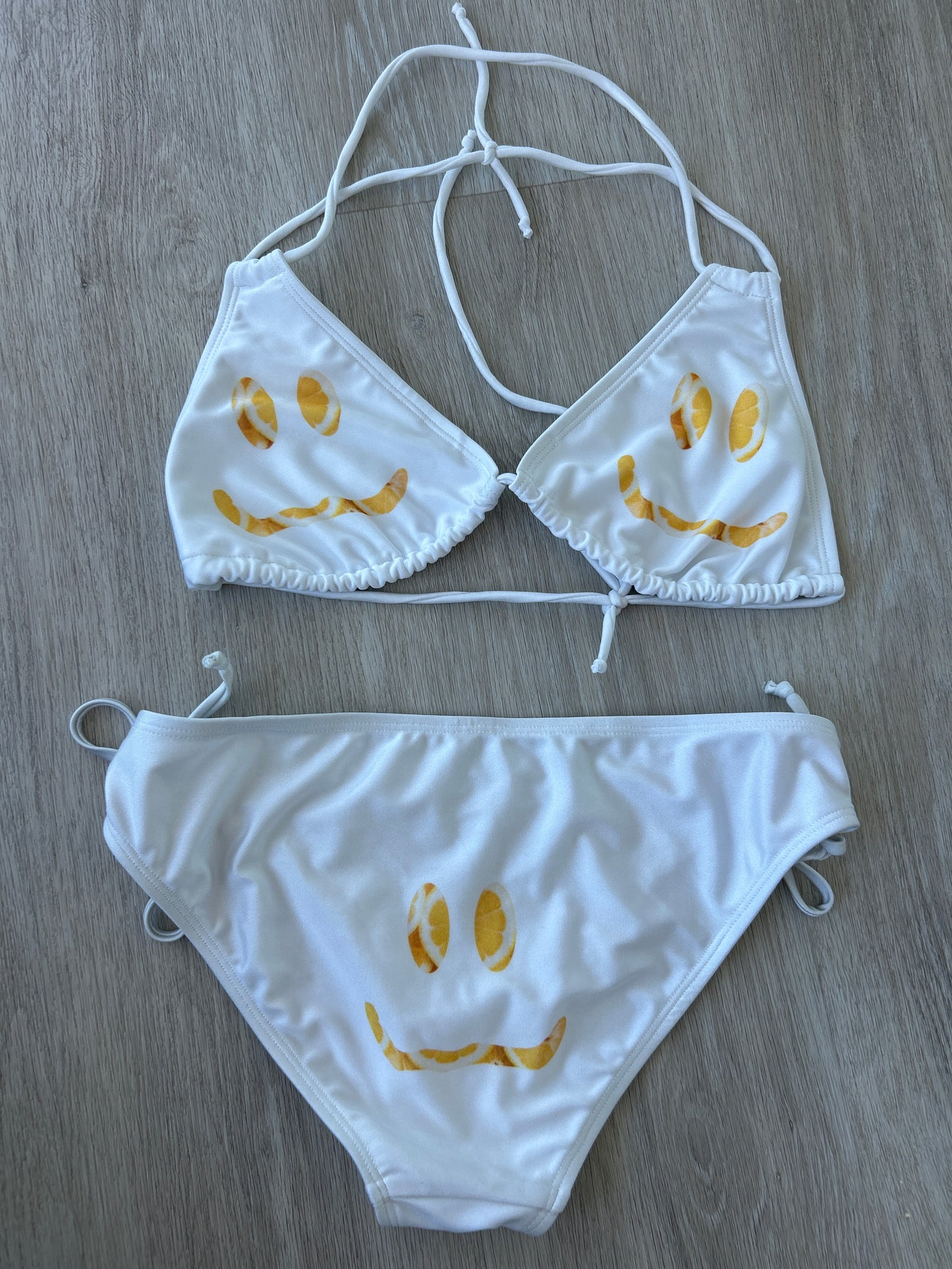 White bikini set with yellow floral patterns on a wooden surface