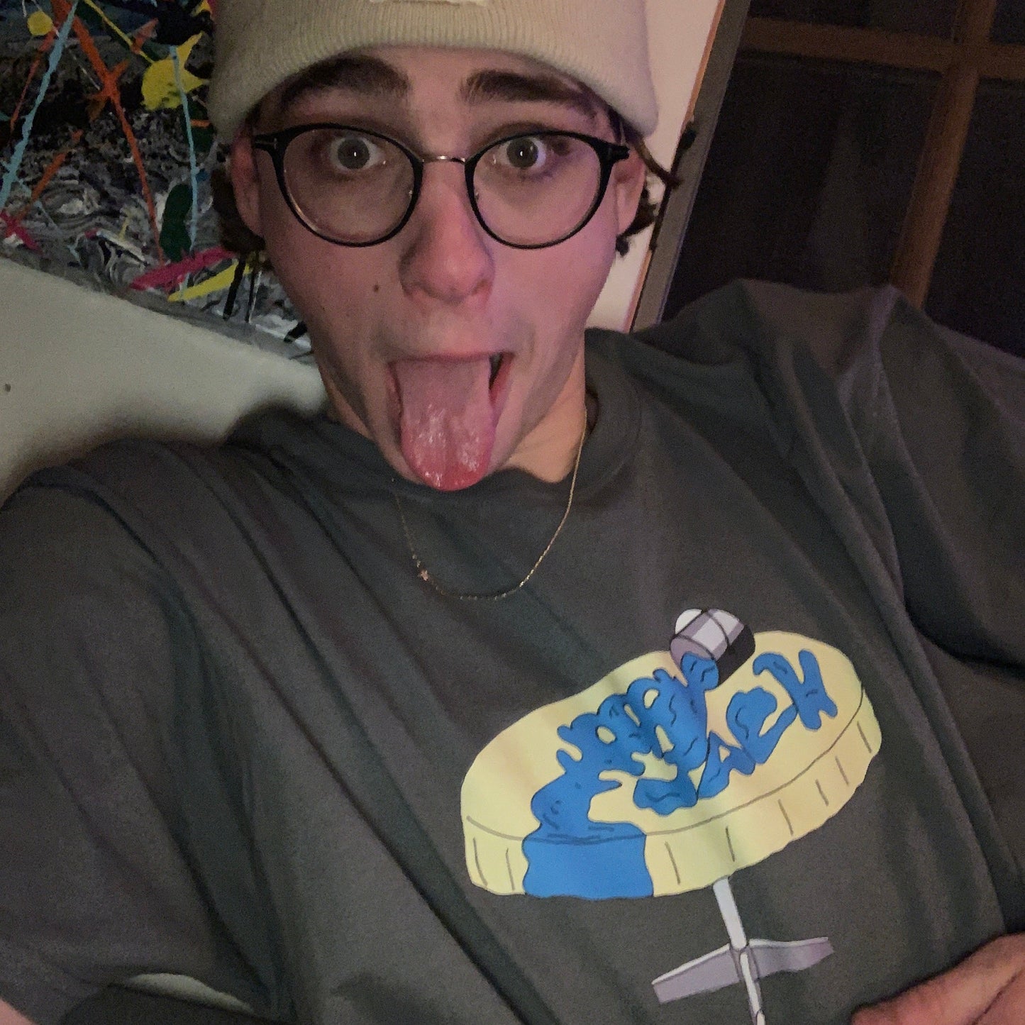 Person wearing a gray t-shirt with a graphic design, sitting on a colorful rug.