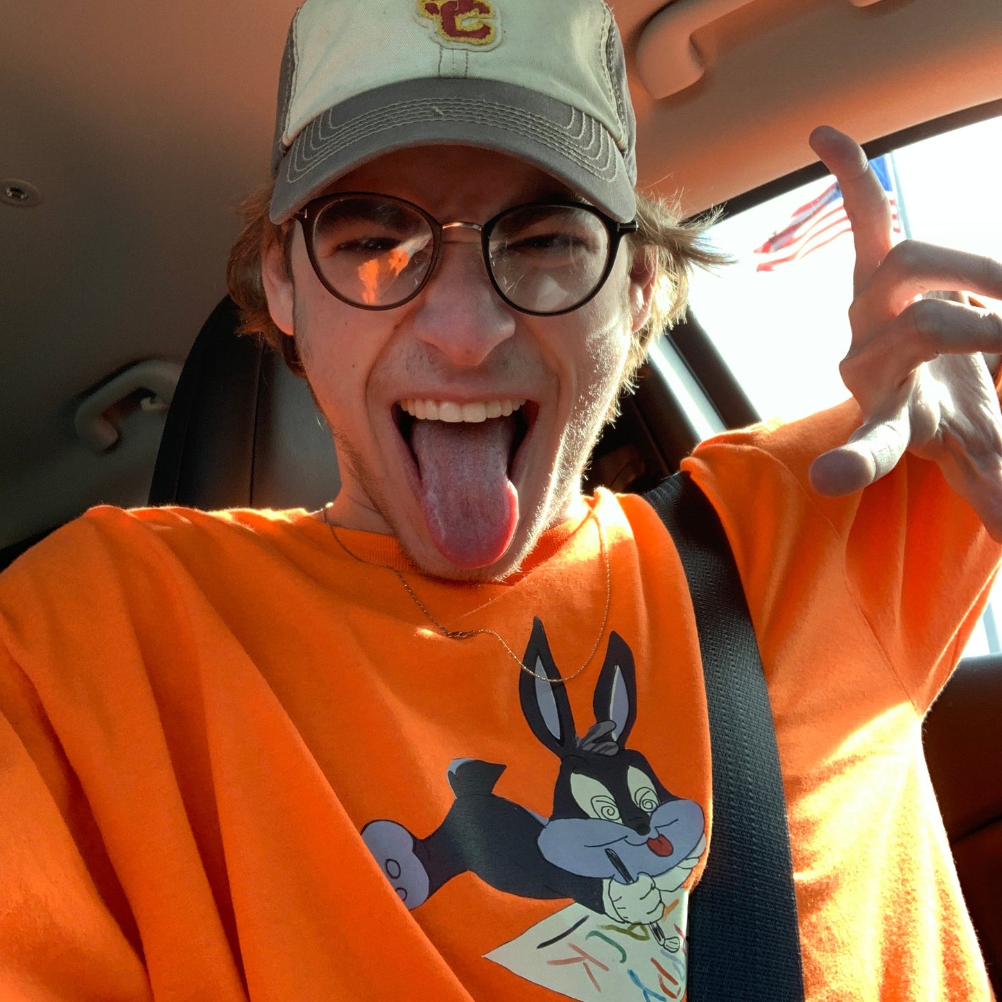 Person wearing an orange shirt with a cartoon character, sitting inside a vehicle.