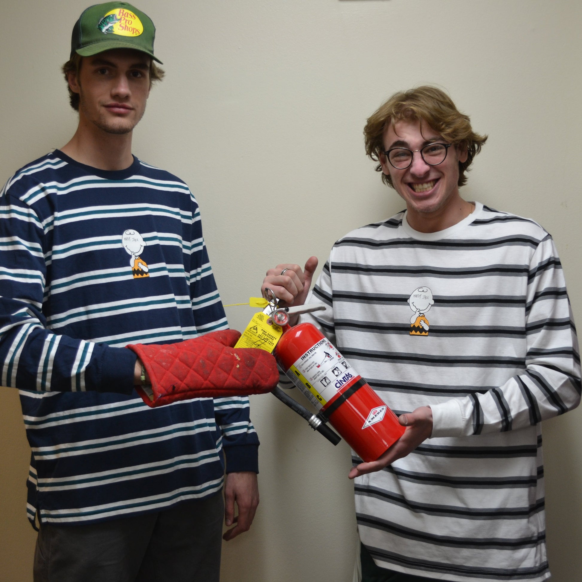 Two people holding a fire extinguisher in a room with a door.